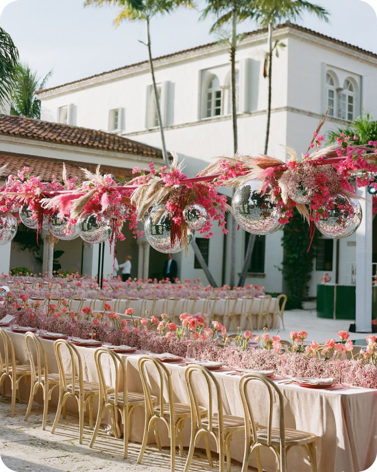 Anna Lucia Events proves that reception details are where the story lives — disco balls nestled into cascading dried florals, blush linens, and a sea of pink arrangements that made this courtyard feel like it was designed for exactly one couple.